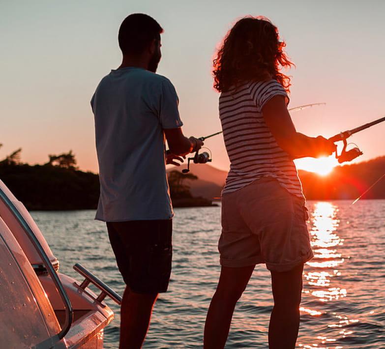 Deux personnes qui pêchent face à un coucher de soleil